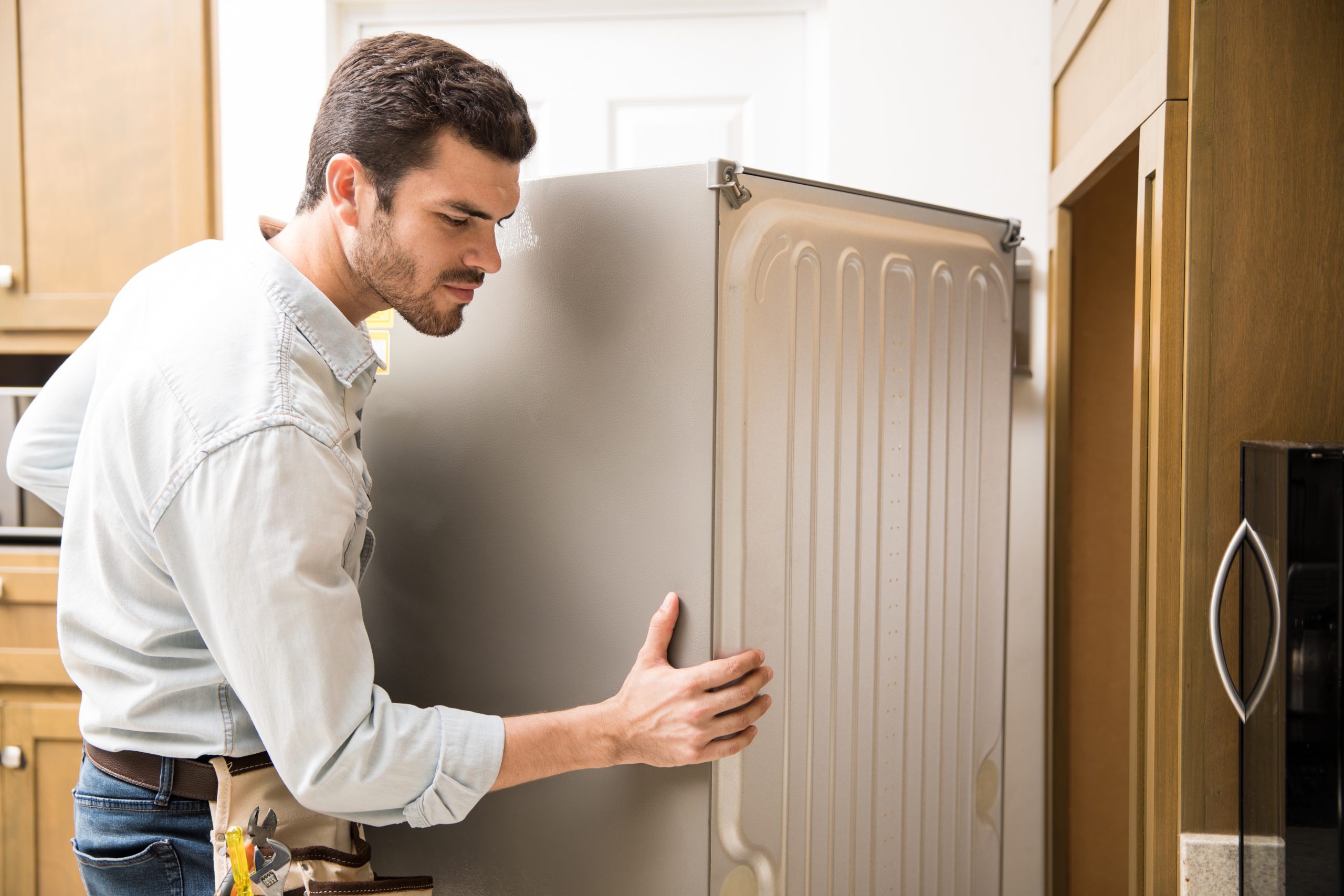 electrician moving a fridge in a kitchen